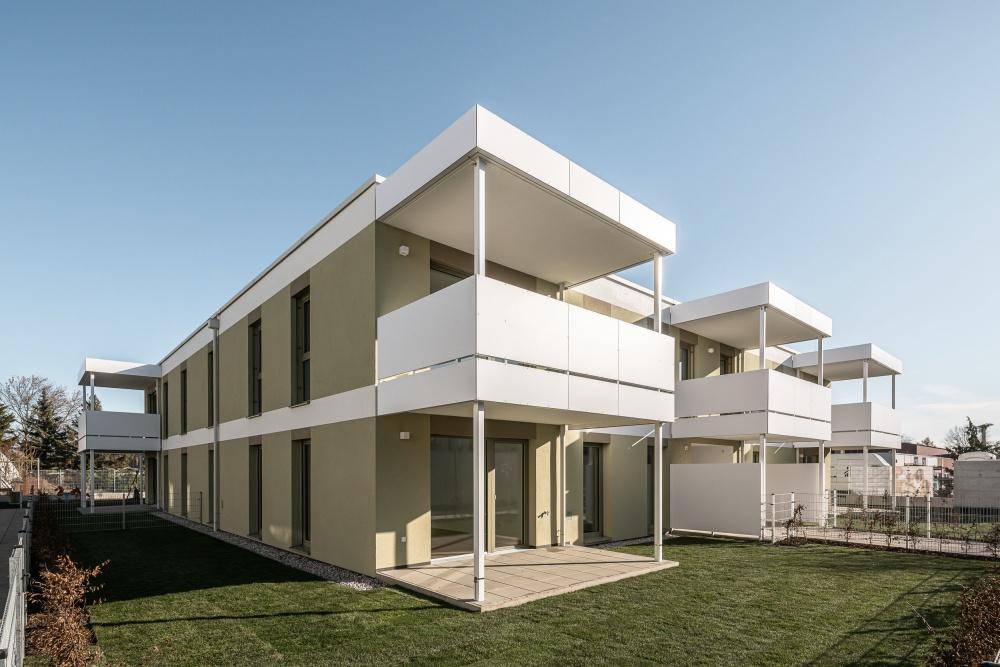 Neubau-Reihenhäuser mit hellen Fassaden, großen Fenstern und privaten Terrassenbereichen.