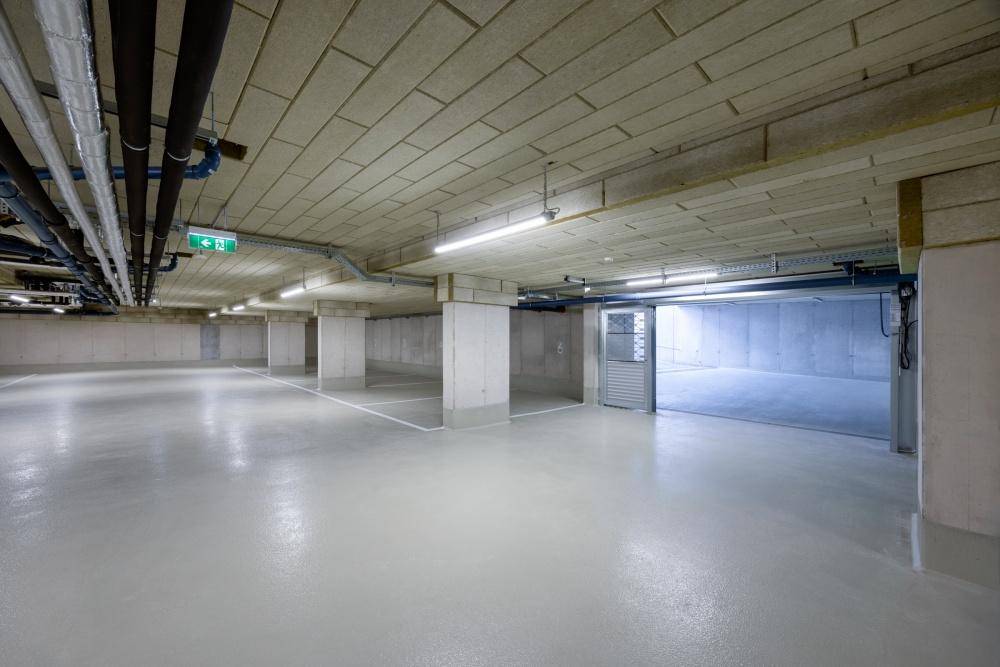 Geräumige und gut beleuchtete Tiefgarage mit vielen Stellplätzen und moderner Infrastruktur.