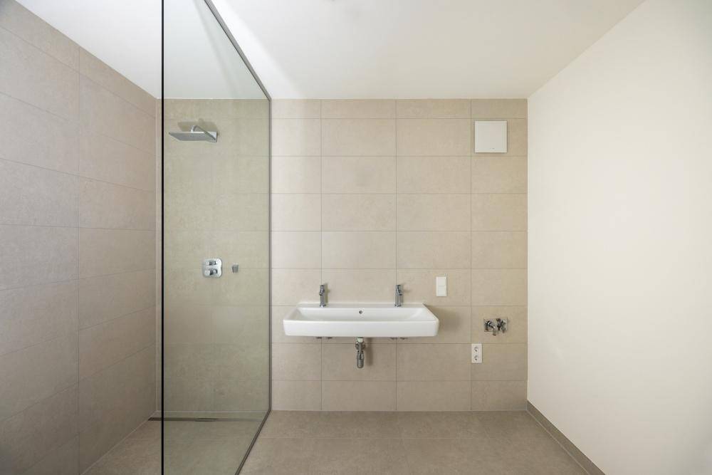 Modernes Badezimmer mit begehbarer Dusche, Doppelwaschbecken und hellen Fliesen.