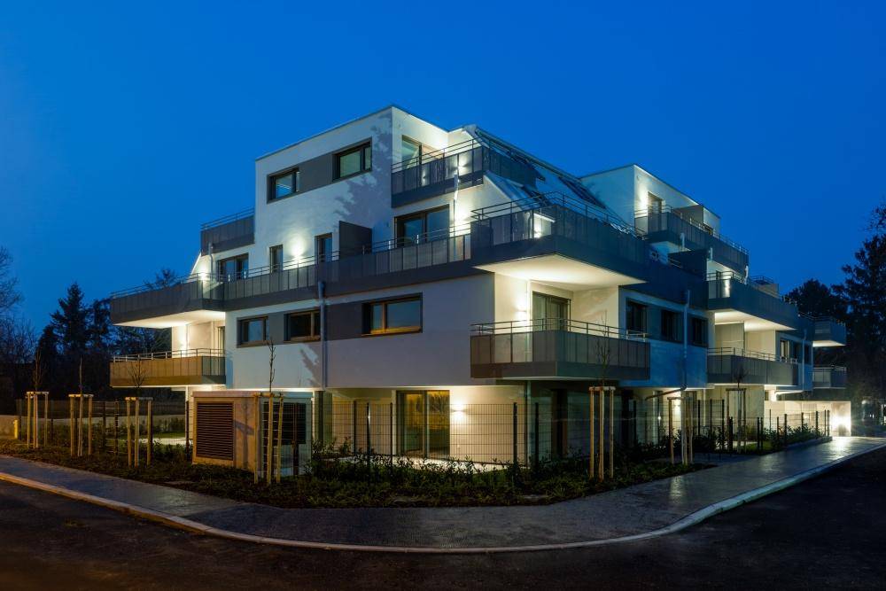 Beleuchtetes modernes Wohngebäude bei Nacht, das die zeitgenössische Architektur hervorhebt.