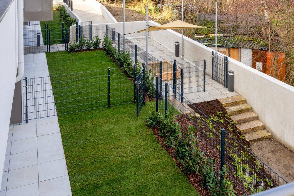 Gepflegter Gartenbereich mit Rasenfläche, Gehwegen und Zäunen, ideal für Erholung im Freien.