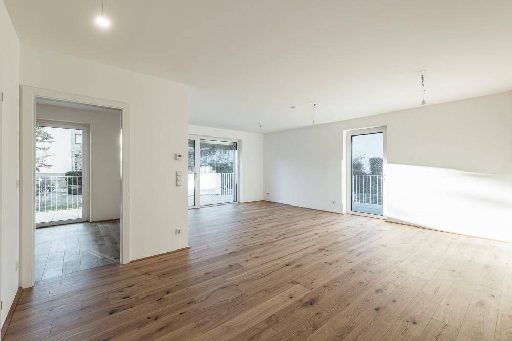 Geräumiger, heller Raum mit Holzboden und mehreren Fenstern für optimale Belichtung.