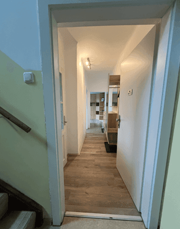 Langer Flur mit Holzoptikboden und Zugang zu weiteren Räumen.