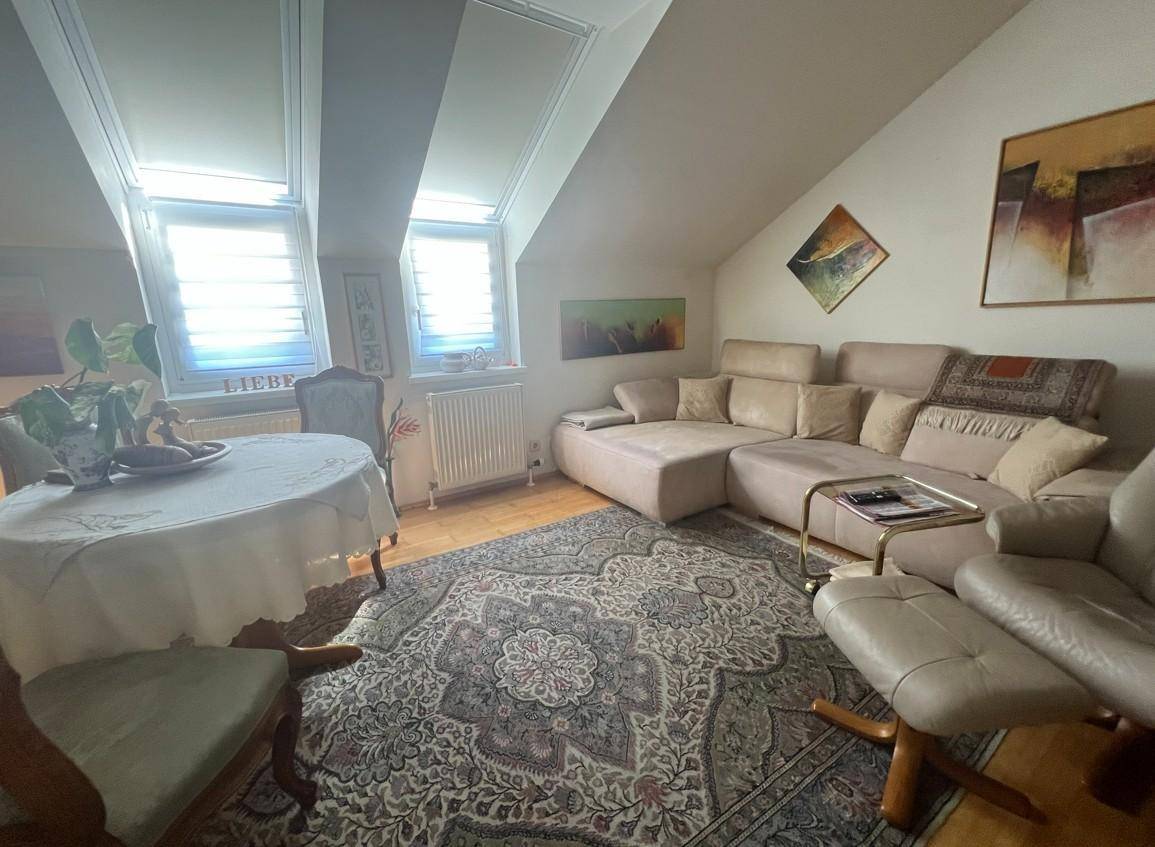 Helles Wohnzimmer im Dachgeschoss mit schrägen Decken, Dachfenstern und gemütlicher Sofalandschaft.