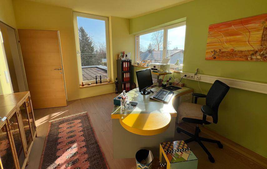 Helles Büro mit grünen Wänden, großzügigen Fenstern und einem Schreibtisch mit Blick ins Freie.