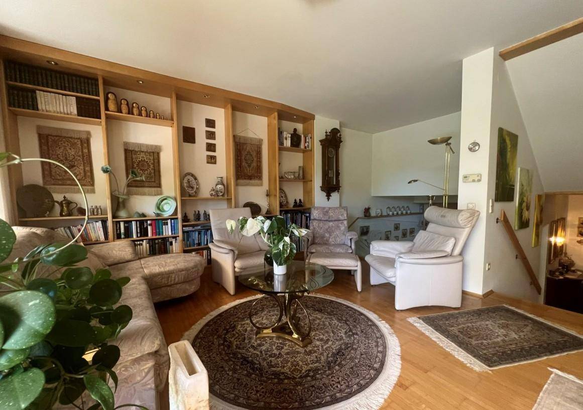 Geräumiges Wohnzimmer mit großer Bücherwand, bequemen Sofas und traditionellen Teppichen.