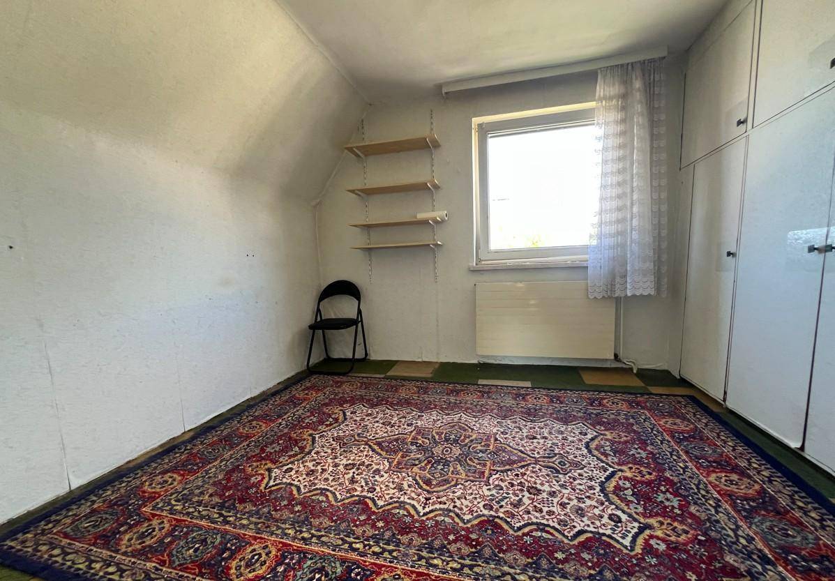 Gemütliches Dachzimmer mit Teppichboden, Fenster und Einbauschränken, ideal als Schlaf- oder Gästezimmer.