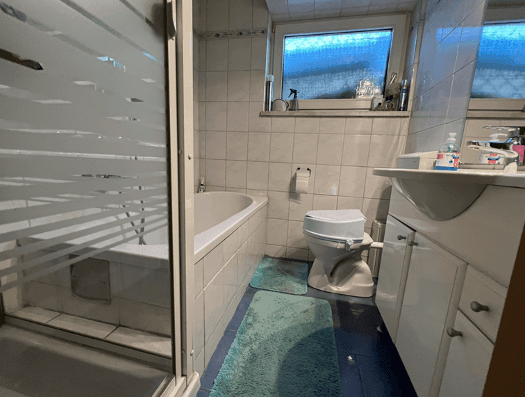 Badezimmer mit Badewanne, Duschkabine, WC und Fliesen in hellem Design.