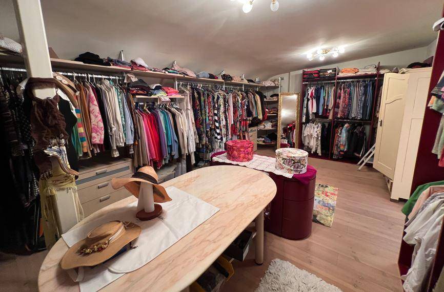 Geräumiger begehbarer Kleiderschrank mit viel Stauraum, Regalen und einer zentralen Ablagefläche.