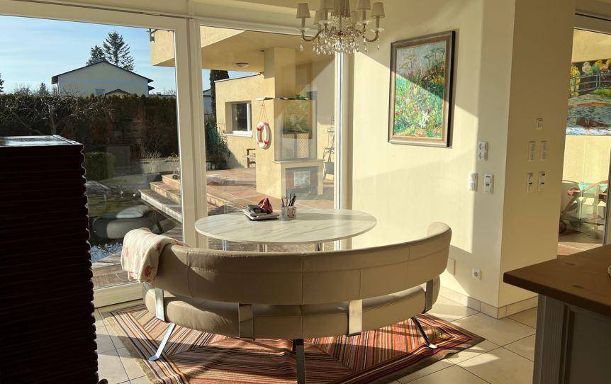 Helle Essecke mit Blick auf den Garten und den Poolbereich durch große Glasschiebetüren.