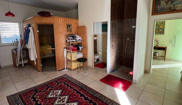 Wellnessbereich mit holzvertäfelter Sauna, moderner Duschkabine und Fliesenboden.