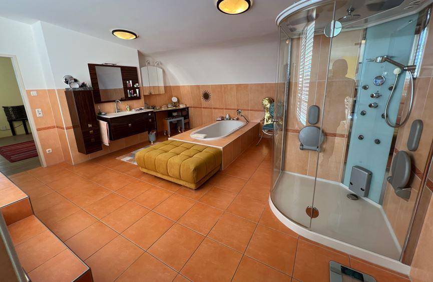 Großes Badezimmer mit Badewanne, moderner Duschkabine und Doppelwaschbecken auf Holzunterschrank.