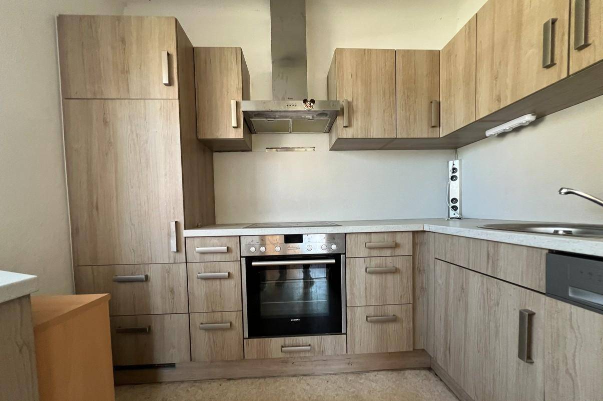 Funktionale Einbauküche mit Holzoptik-Fronten, integriertem Backofen und Dunstabzugshaube, bereit zur Nutzung.