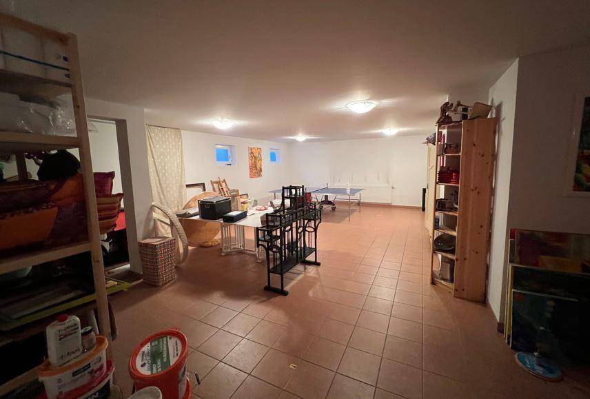 Großer Kellerraum mit Fliesenboden, Regalen und Platz für verschiedene Aktivitäten.