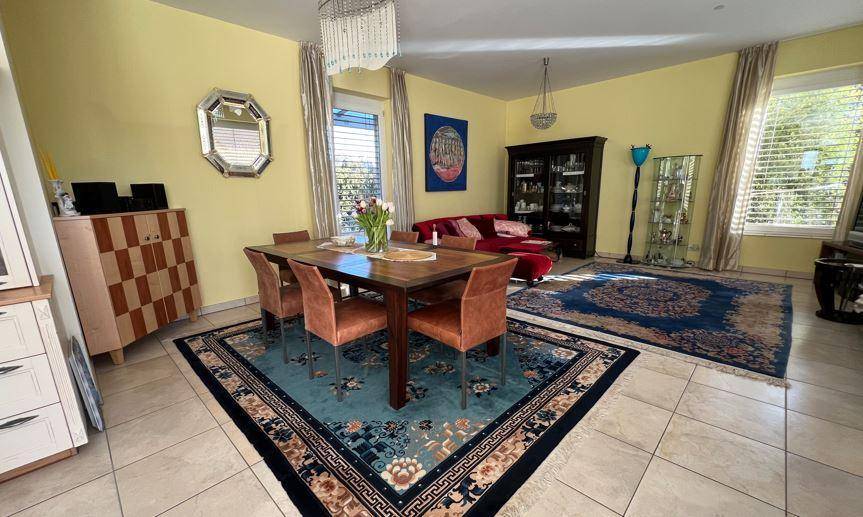 Geräumiger Wohn- und Essbereich mit traditionellen Teppichen, gelben Wänden und einem großen Esstisch.