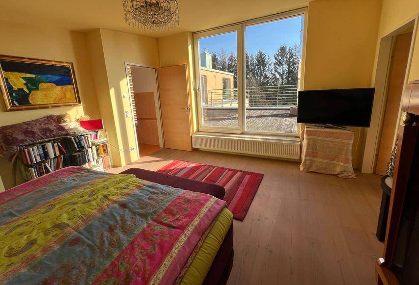 Helles Schlafzimmer mit großen Fenstern, die Zugang zu einer Terrasse bieten und viel Tageslicht hereinlassen.