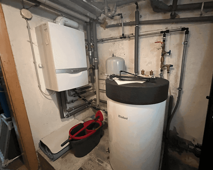 Heizungsraum mit moderner Gastherme und Warmwasserspeicher im Keller.