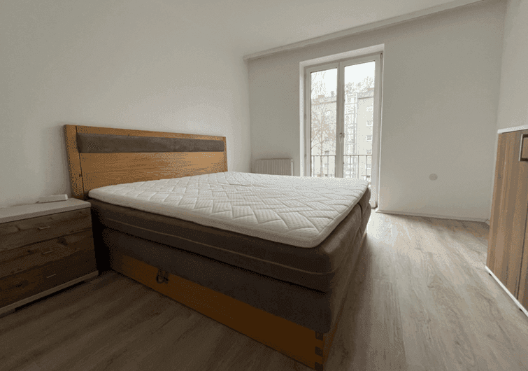 Schlafzimmer mit Doppelbett, Nachttischen und Zugang zu einem französischen Balkon.