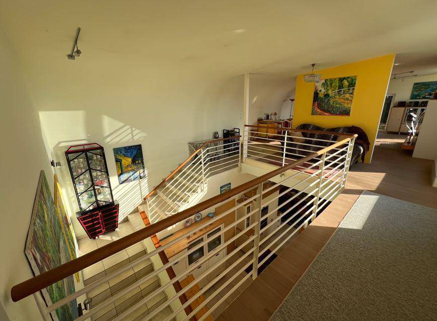 Modernes Treppenhaus mit Metallgeländer und Holzhandlauf, das den offenen Wohnbereich verbindet.