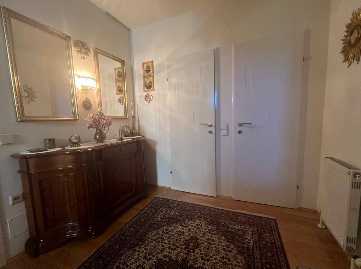 Gemütlicher Flur mit dunklem Holzschrank, dekorativen Spiegeln und einem traditionellen Teppich.