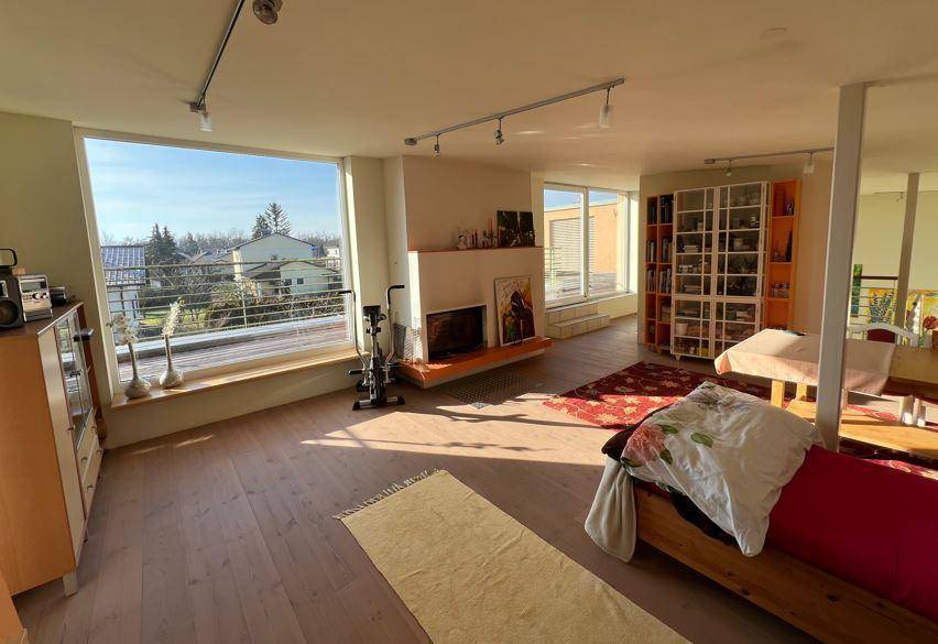 Großzügiges Wohnzimmer mit Holzboden, Kamin und weitem Blick durch expansive Fenster.