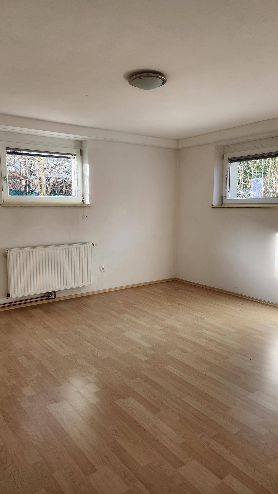 Helles Schlafzimmer mit Laminatboden und zwei Fenstern, unmöbliert und bezugsfertig.