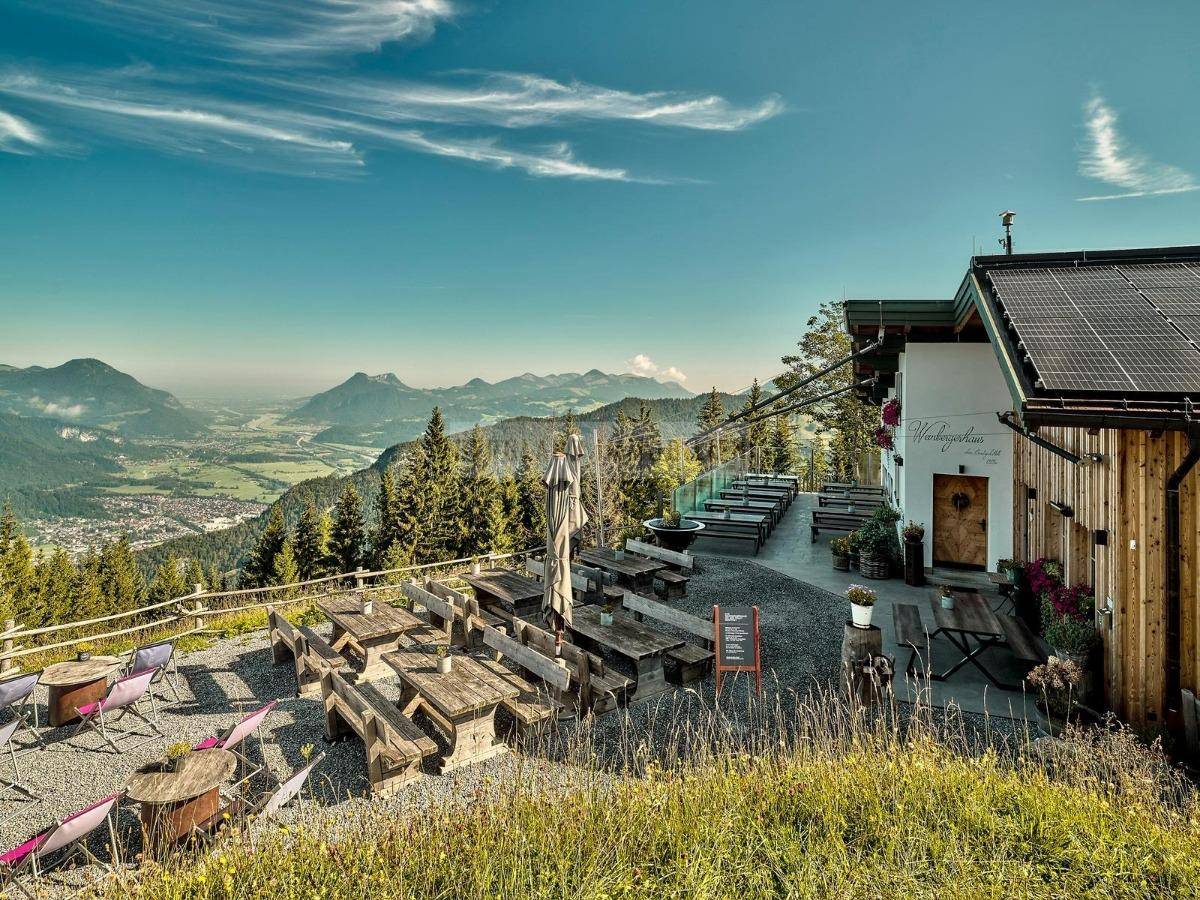 Große Außenterrasse mit Holztischen und Bänken, bietet einen weiten Blick über das Tal und die Berge.