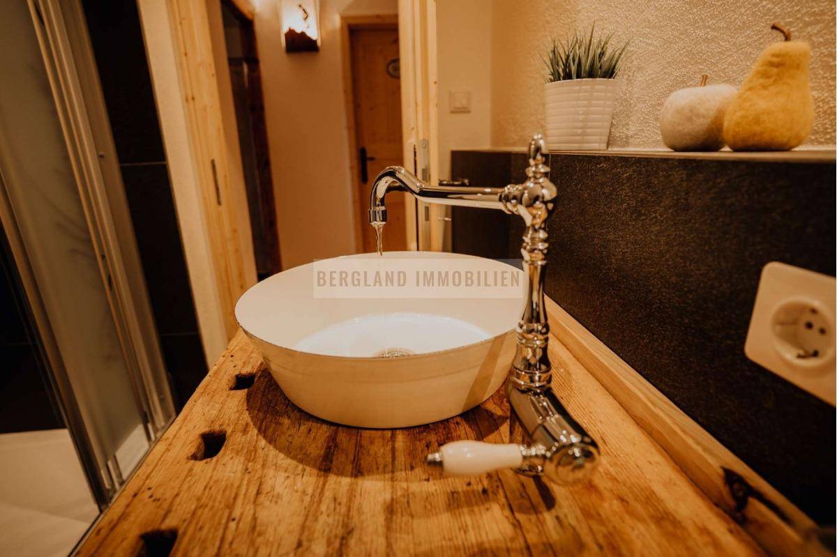 Rustikaler Waschtisch mit einzigartigem Becken und nostalgischem Wasserhahn auf einer Holzplatte.