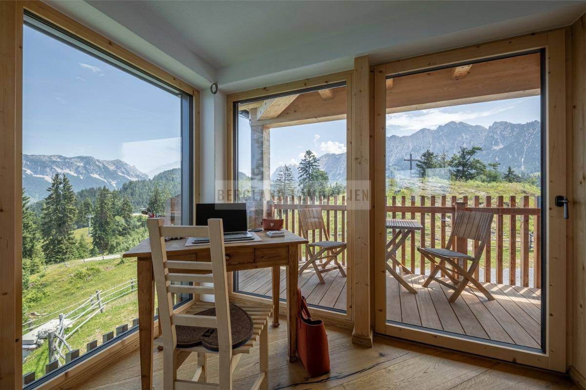 Helles Büro mit Schreibtisch und Stuhl, bietet einen atemberaubenden Panoramablick auf die Berge.