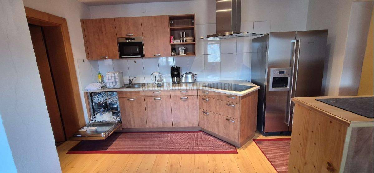 Detailansicht der Holzküche mit integriertem Geschirrspüler, Backofen und großem Kühlschrank.
