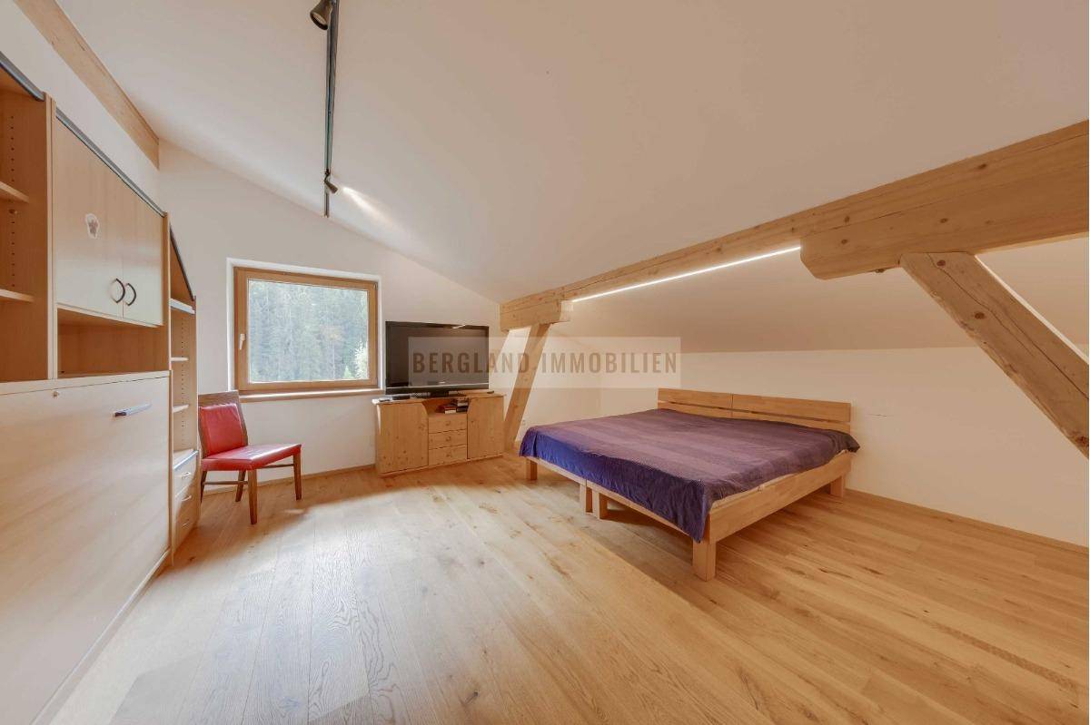 Geräumiges Schlafzimmer im Dachgeschoss mit Holzboden, Dachschrägen und einem praktischen Wandbett.