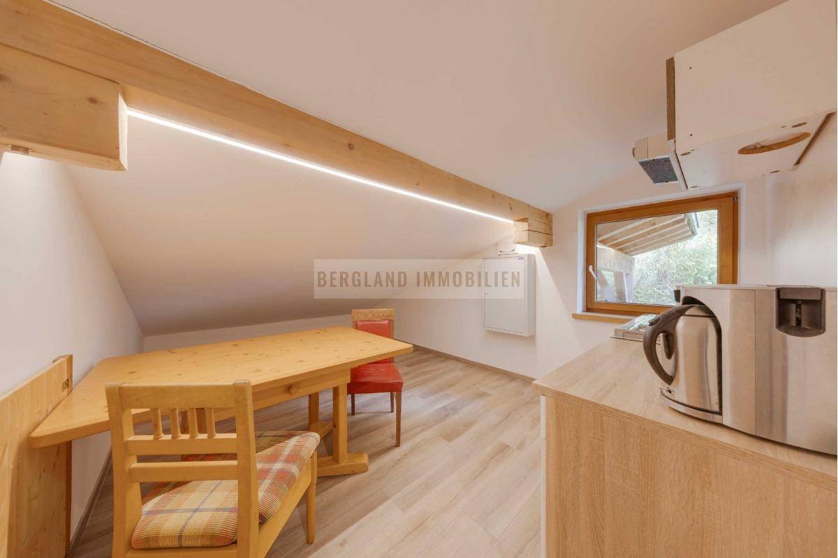 Kleine Küche mit Essbereich im Dachgeschoss, Holztisch, Dachschrägen und sichtbaren Holzbalken.