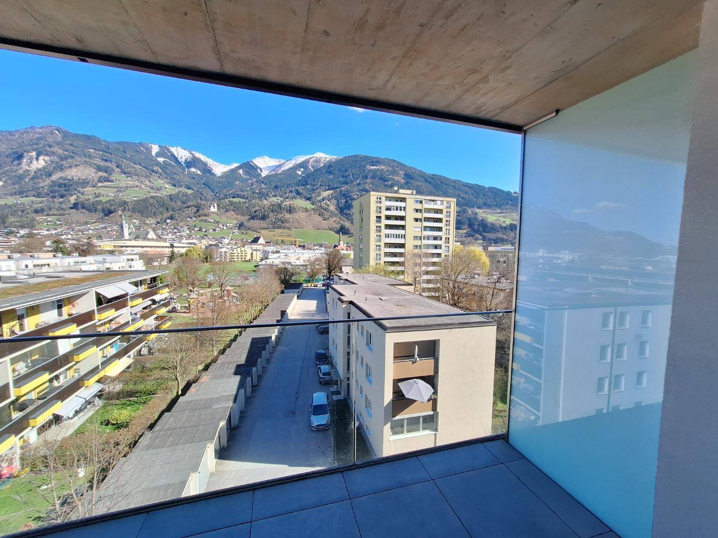 Balkon mit Glasbrüstung bietet einen weiten Blick auf die Stadt und die umliegende Berglandschaft.