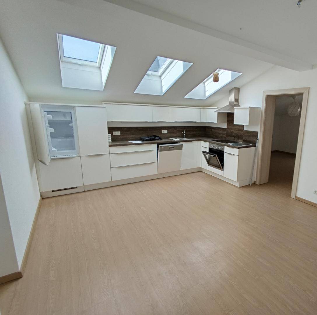 Helle, moderne Küche mit weißen Schränken, Dachfenstern und neuen Einbaugeräten.