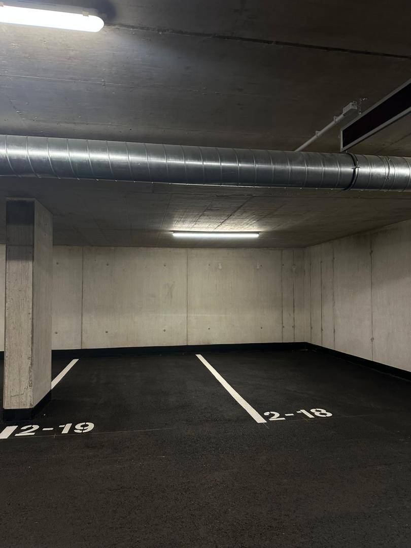 Saubere und gut beleuchtete Tiefgarage mit markierten Parkplätzen und Betonwänden.