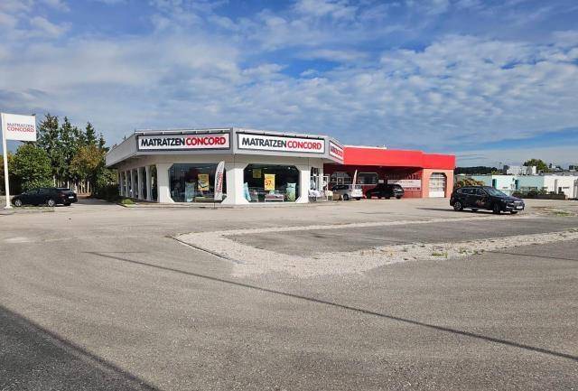 Ansicht eines Geschäftsgebäudes mit großem Parkplatz und Beschilderung unter blauem Himmel.