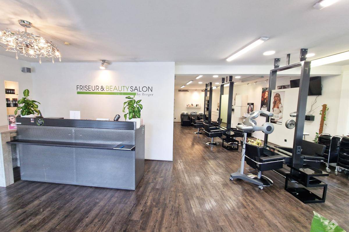 Empfangsbereich eines Friseur- und Schönheitssalons mit moderner Theke und Blick in den Salon.