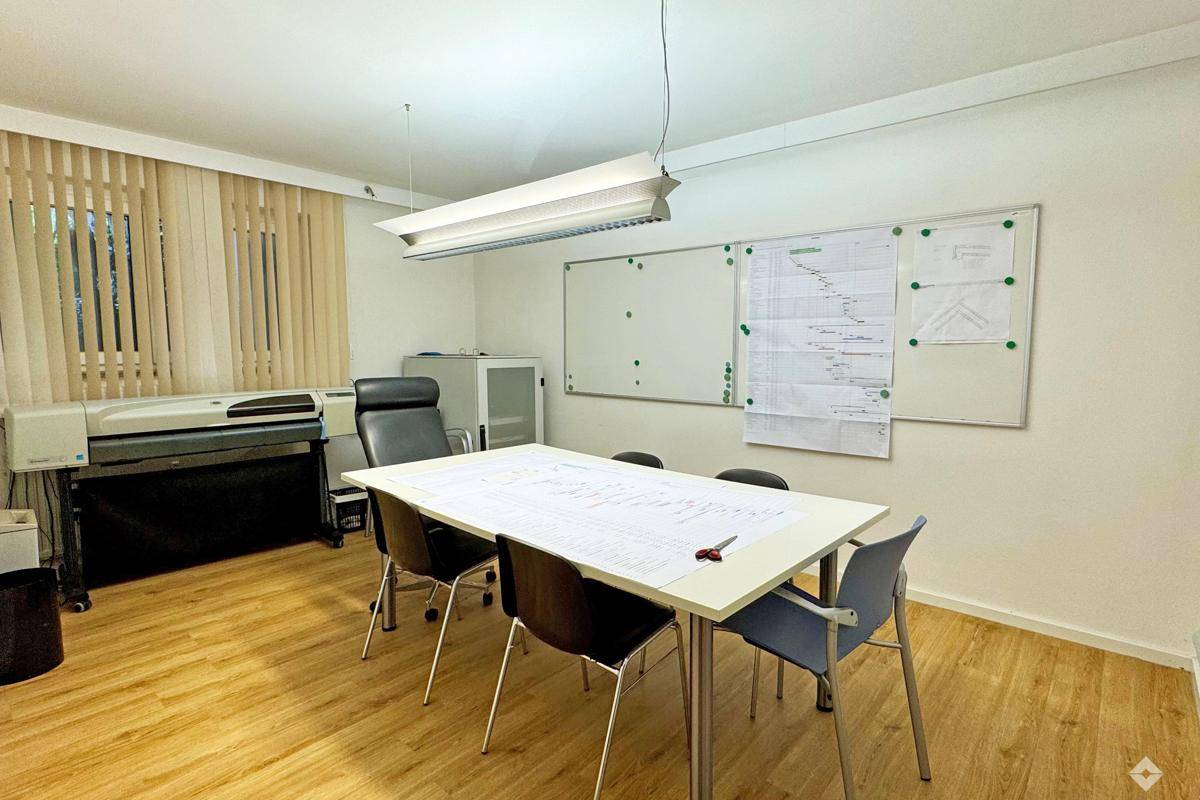 Offener Bürobereich mit Arbeitsplätzen, Raumteilern und einem Kopierer, ideal für Teamarbeit.