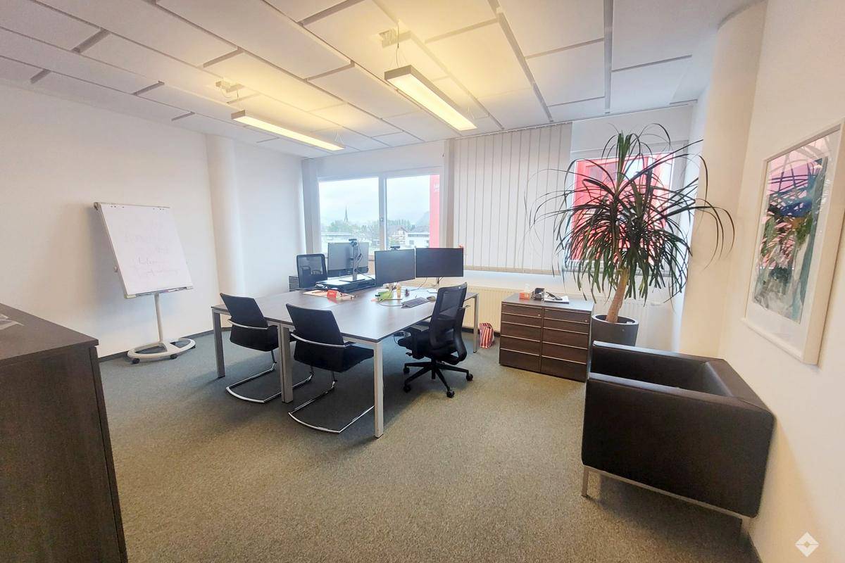 Geräumiges Büro mit mehreren Arbeitsplätzen, großen Fenstern und Blick auf die Umgebung.