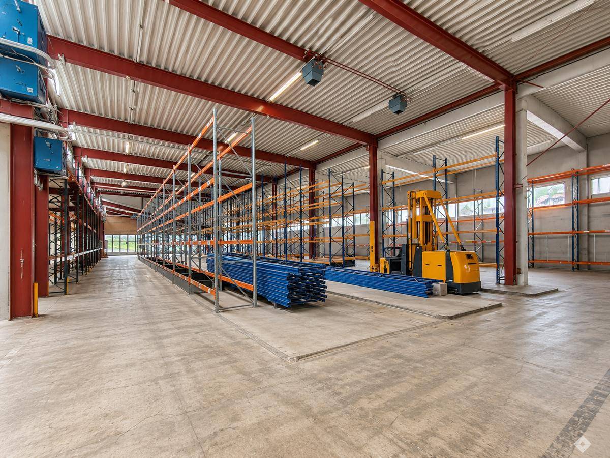 Weitläufige Lagerhalle mit Regalsystemen, Gabelstapler und robustem Betonboden sowie großen Fenstern.