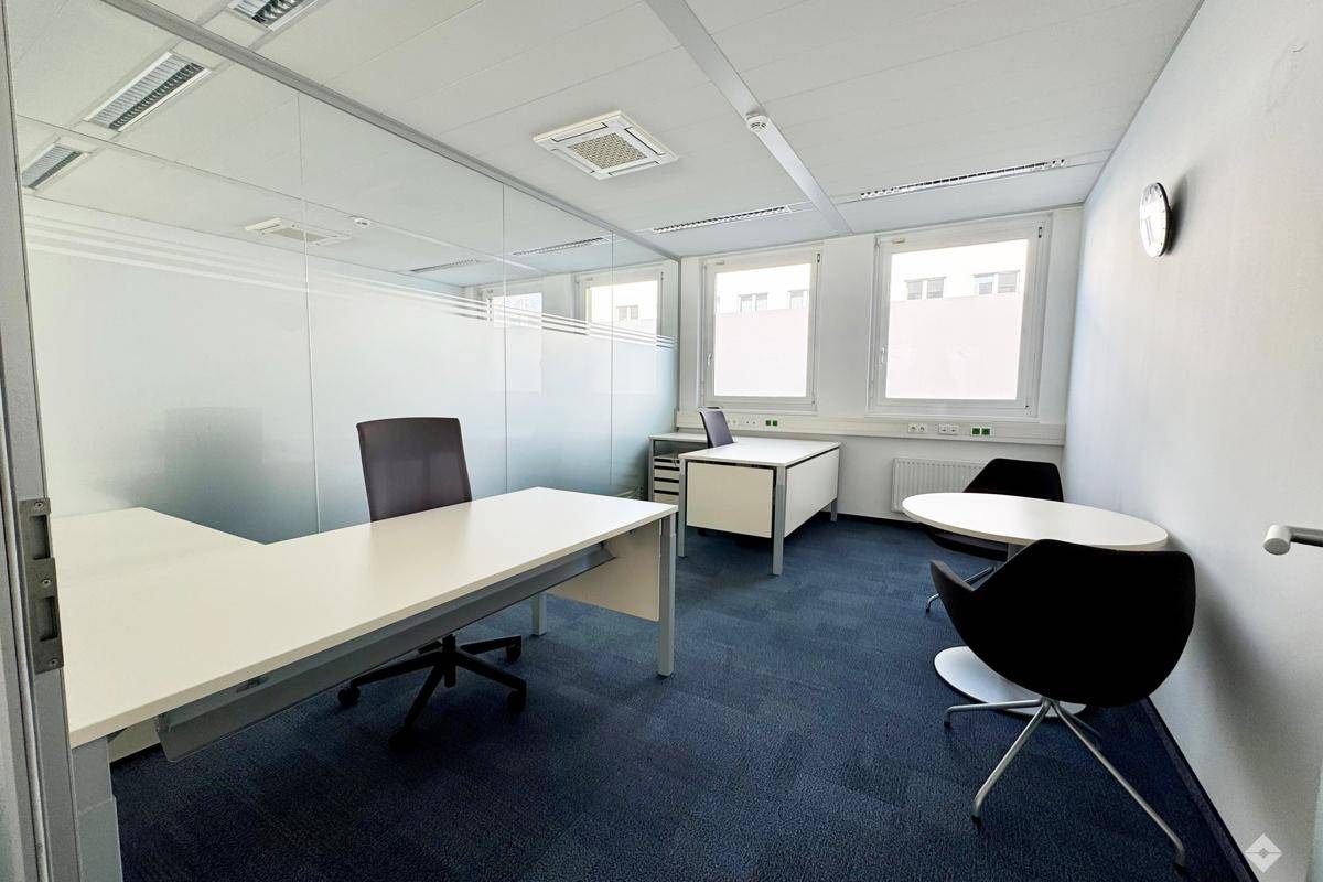 Helles Büro mit mehreren Arbeitsplätzen, Besprechungstisch und großen Fenstern für viel Tageslicht.