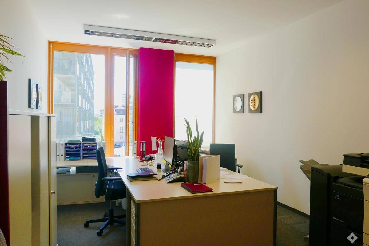Geräumiges Büro mit großen Fenstern, Blick ins Grüne und mehreren Arbeitsplätzen.