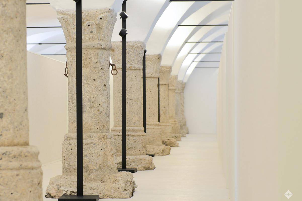 Heller Flur mit beeindruckenden Steinsäulen und gewölbter Decke, ergänzt durch moderne Beleuchtung.