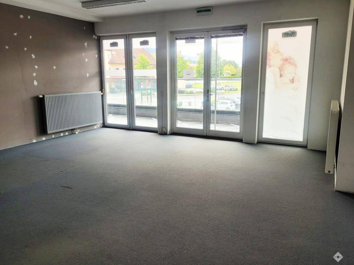 Helles Büro mit dunklem Fliesenboden, großem Fenster und einer farbenfrohen Akzentwand.