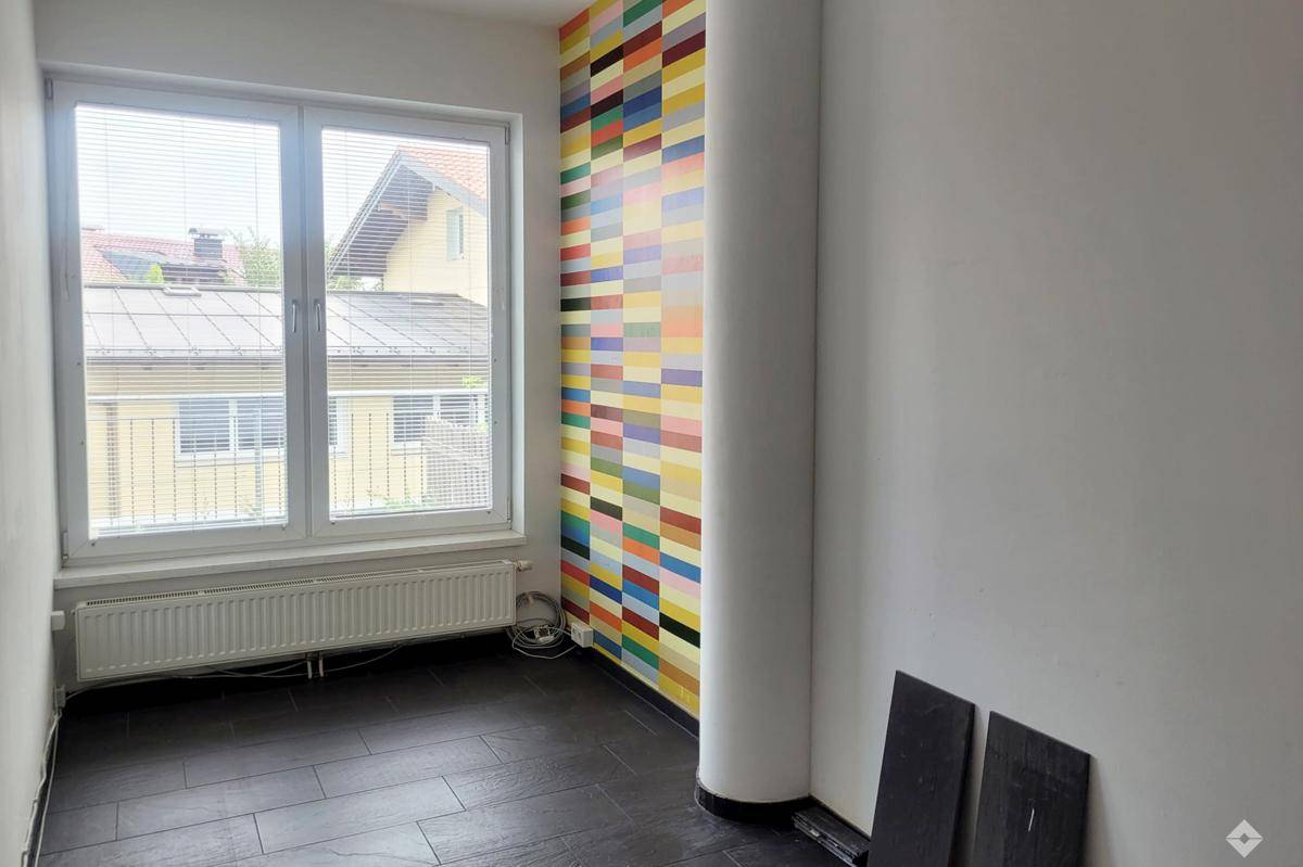 Modernes Geschäftsgebäude mit runder Architektur, großen Glasflächen und verschiedenen Ladenlokalen.