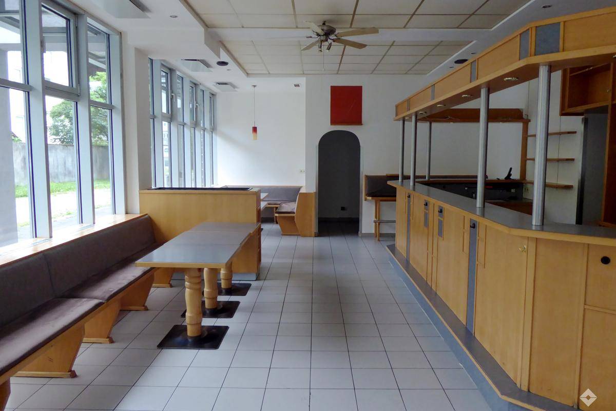Heller Gewerberaum mit Sitzbänken, Fliesenboden und Deckenventilator, ideal für Gastronomie.