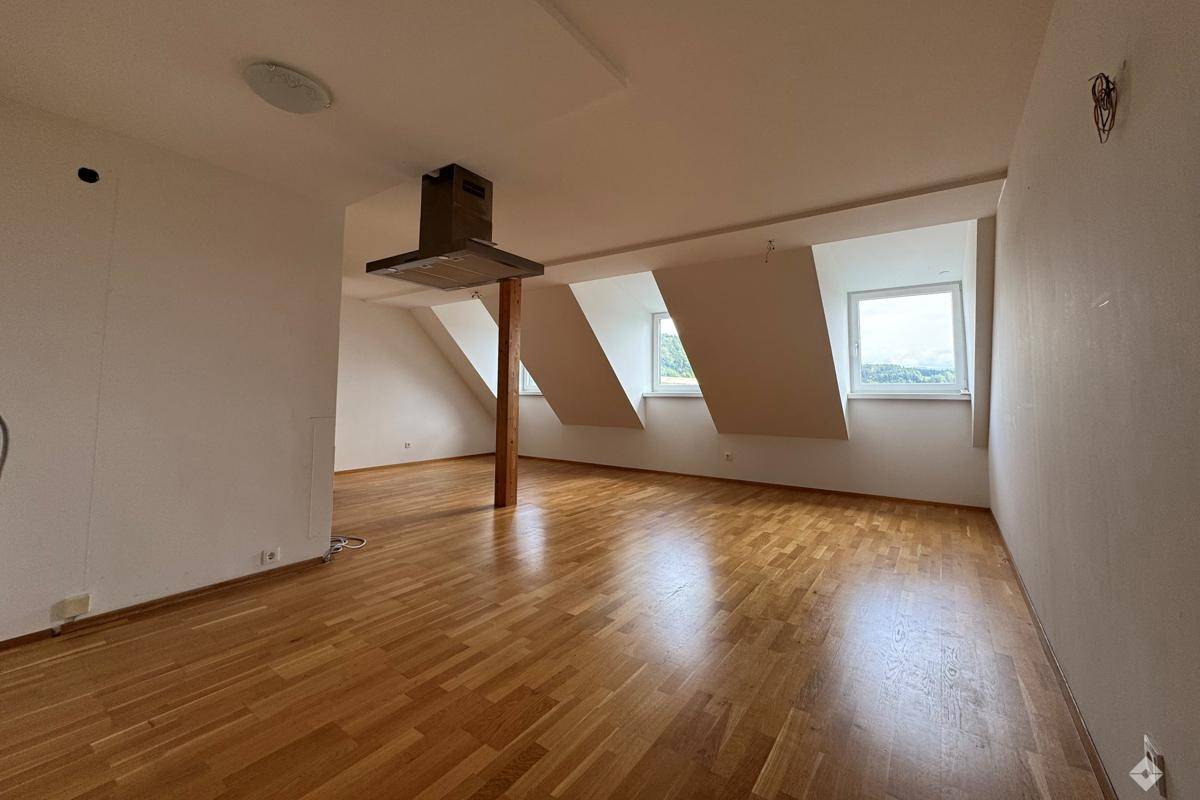 Unfertige Küche mit Holzboden, Dunstabzugshaube und vorbereiteten Anschlüssen für Küchengeräte.