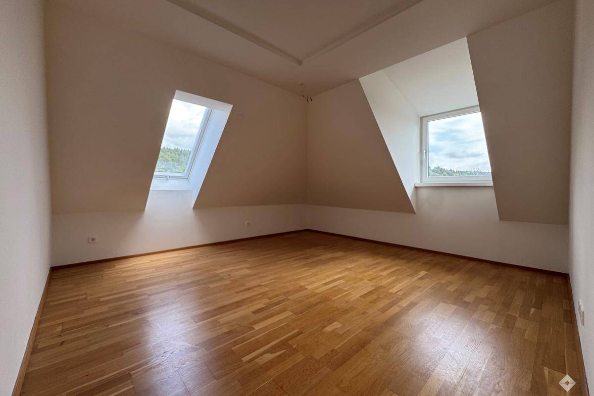 Gemütliches Zimmer mit Holzboden, Dachschräge und einem Dachfenster, ideal als Schlaf- oder Arbeitszimmer.