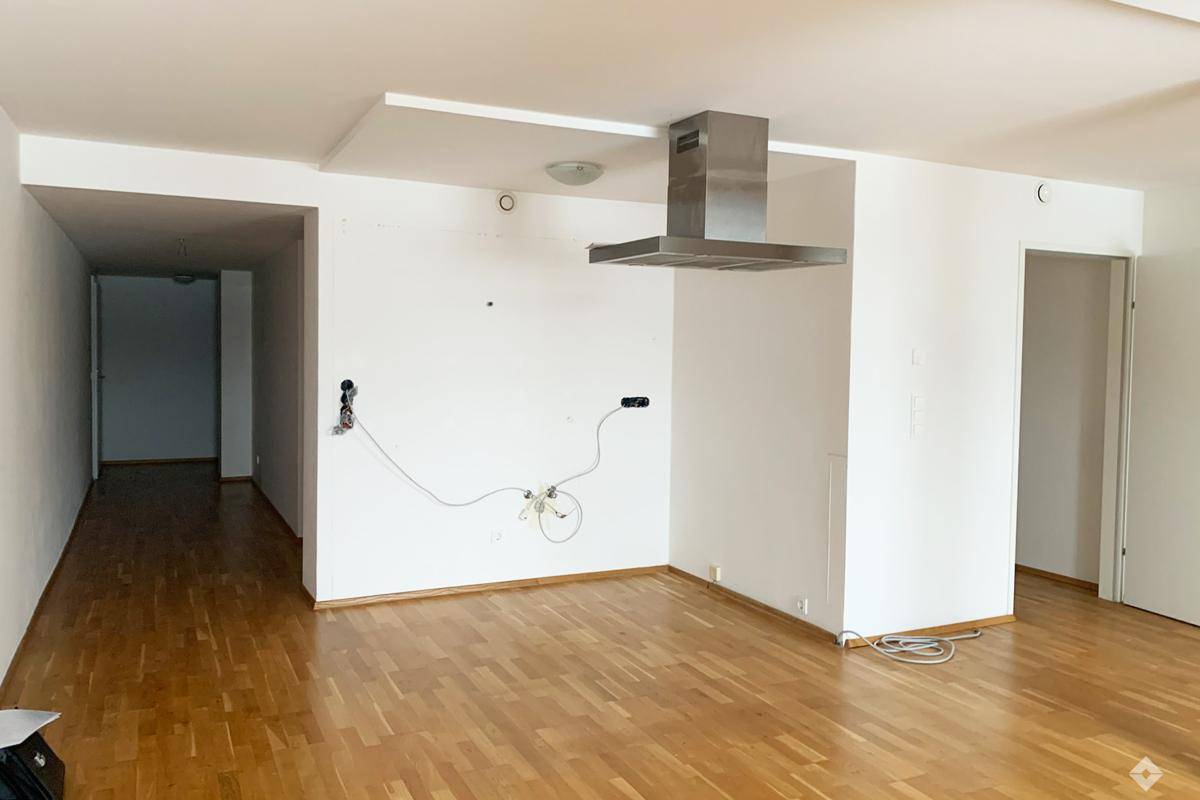 Helles Schlafzimmer mit Holzboden, Dachschrägen und zwei Fenstern, darunter ein Dachfenster.