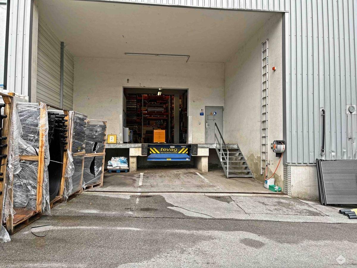 Außenansicht eines Gewerbegebäudes mit moderner Fassade vor einer Bergkulisse.